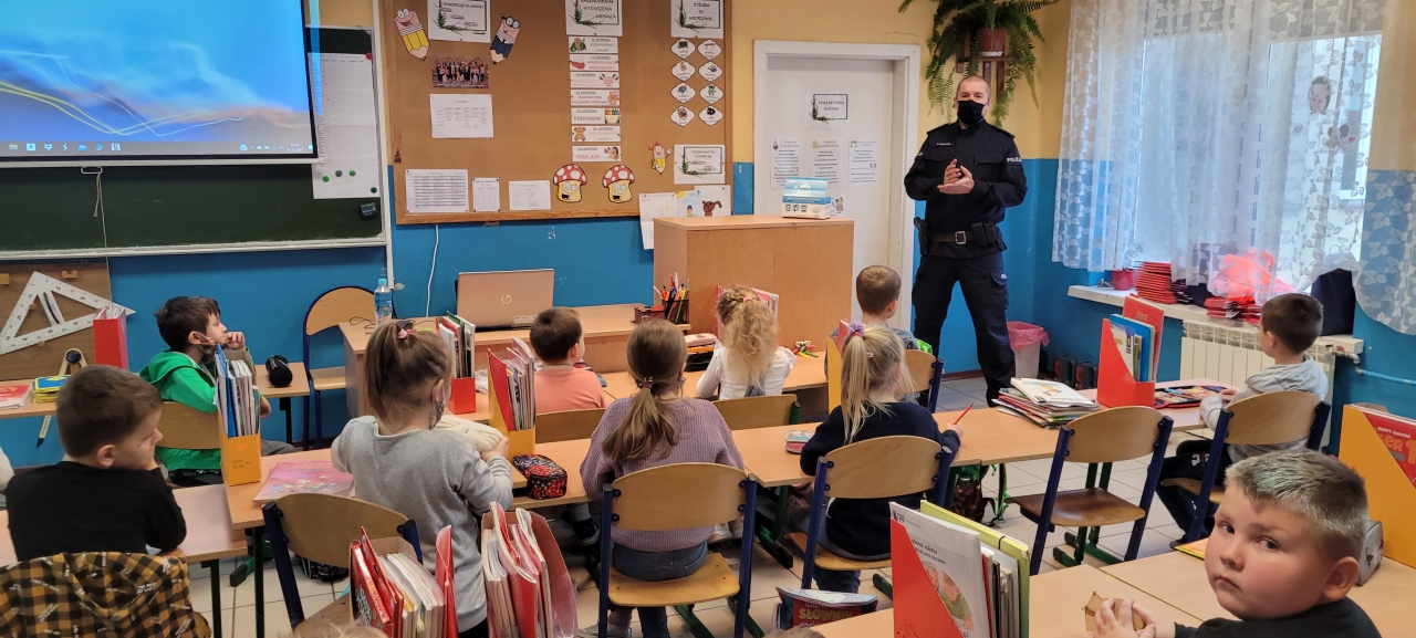 Policjant tłumaczy dzieciom w klasie zasady bezpieczeństwa