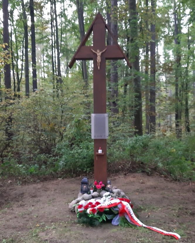 Krzyż drewniany stojący w lesie.