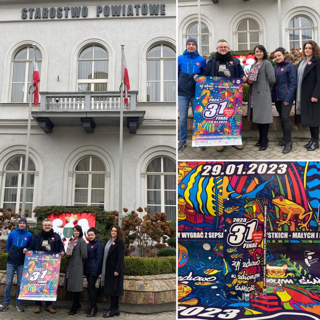 Pracownicy Starostwa stoją przed budynkiem Starostwa z puszką i plakatem promującymi 31. finał WOŚP.