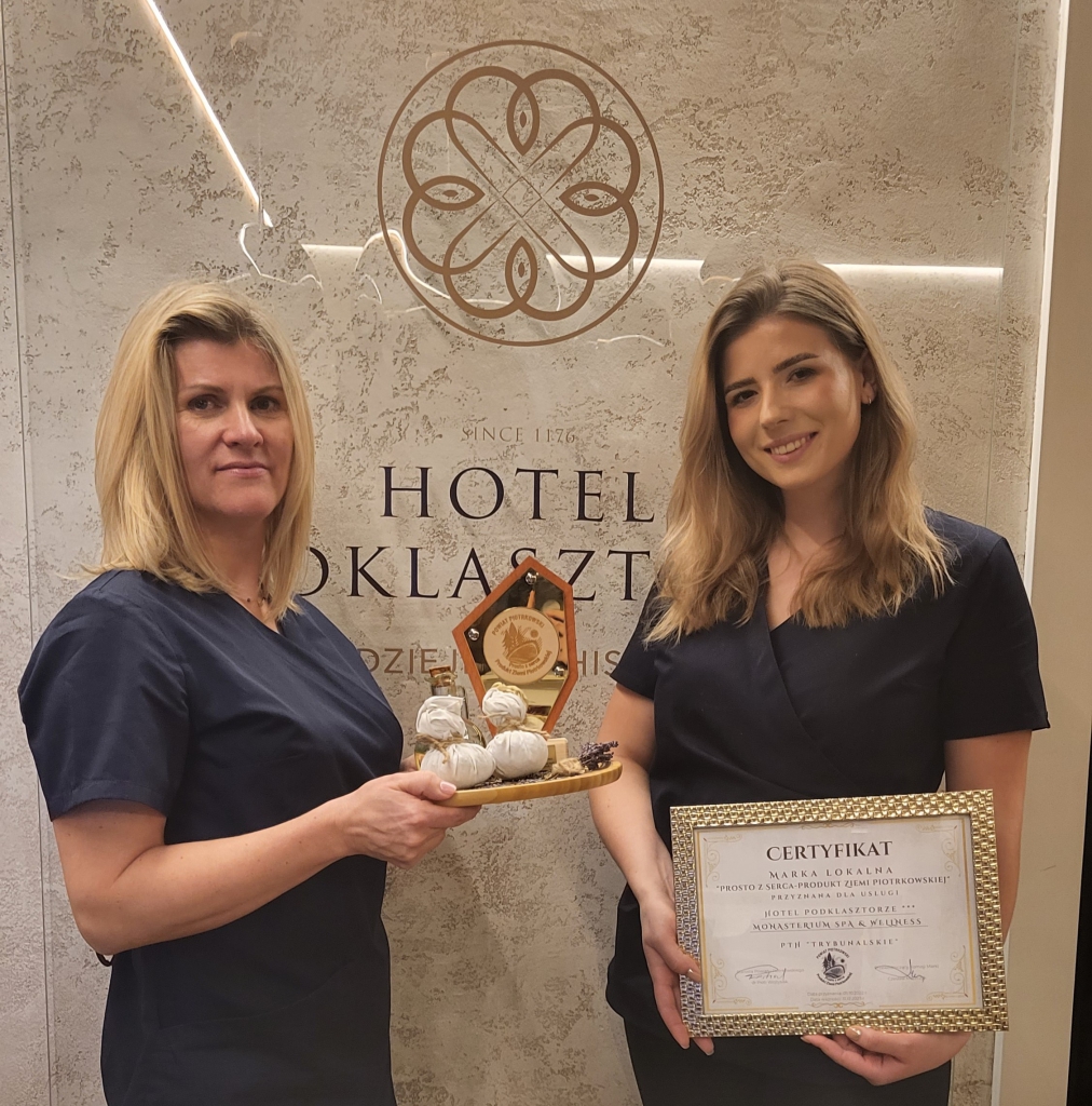 Pracownicy Spa wraz ze swoimi produktami, certyfikatem Marki lokalnej prosto z serca przyznanym przez Powiat Piotrkowski oraz statuetką z napisem powiat Piotrkowski prosto z serca. Produkt Ziemi Piotrkowskiej. W tle logo oraz napis Hotelu Podklasztorze.