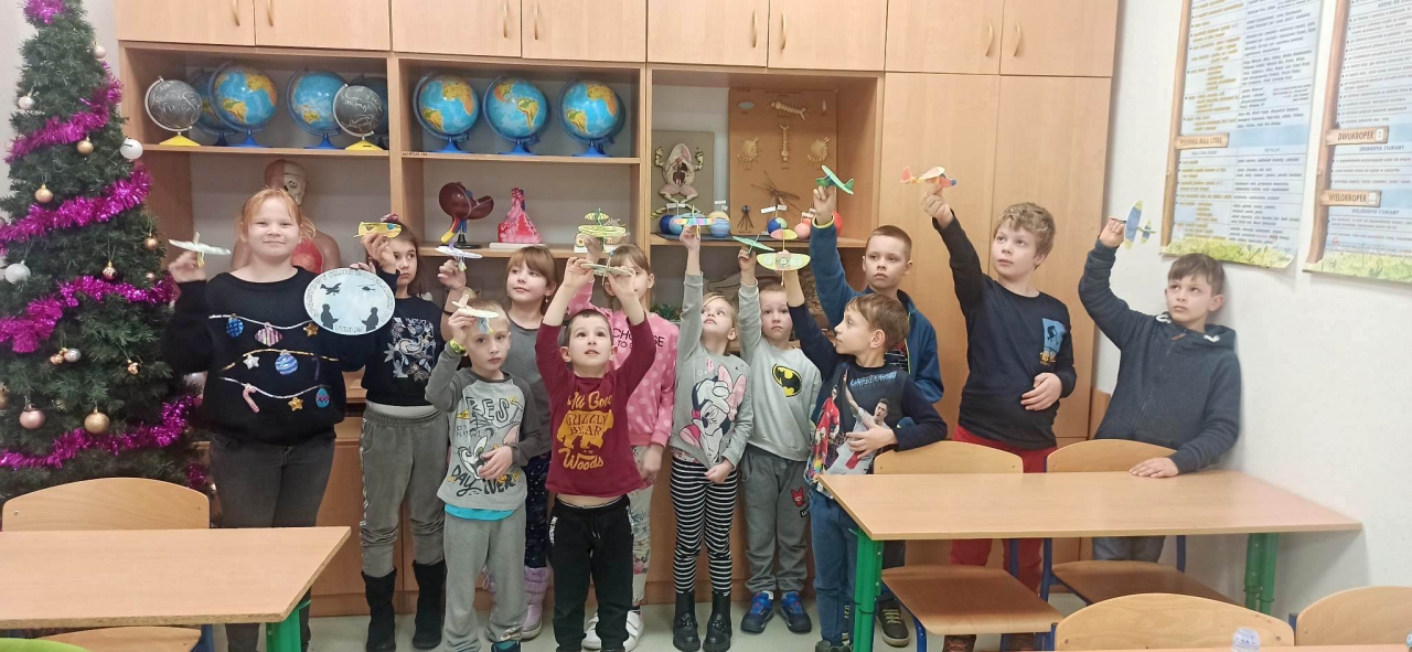 Dzieci znajdują się w pomieszczeniu. obok stoi choinka