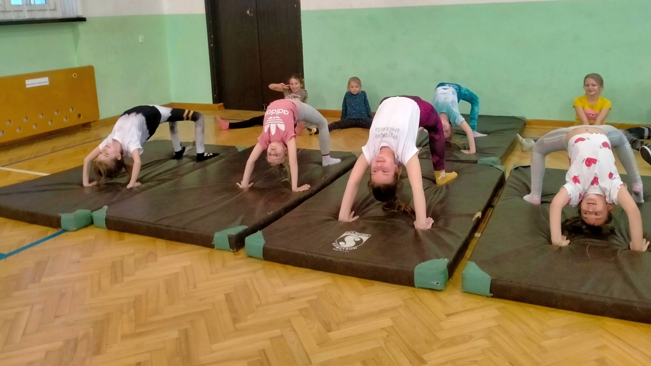 Dzieci znajdują się w pomnieszczeniu podczas zajęć sportowych.