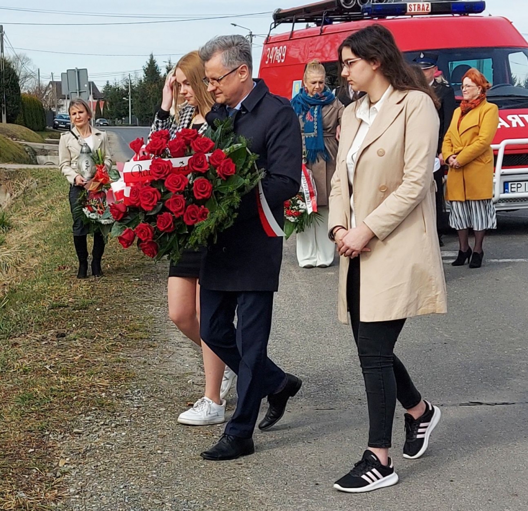 mieszkańcy składają kwiaty, pomnik upmiętniający śmierć mieszkańców Bujen