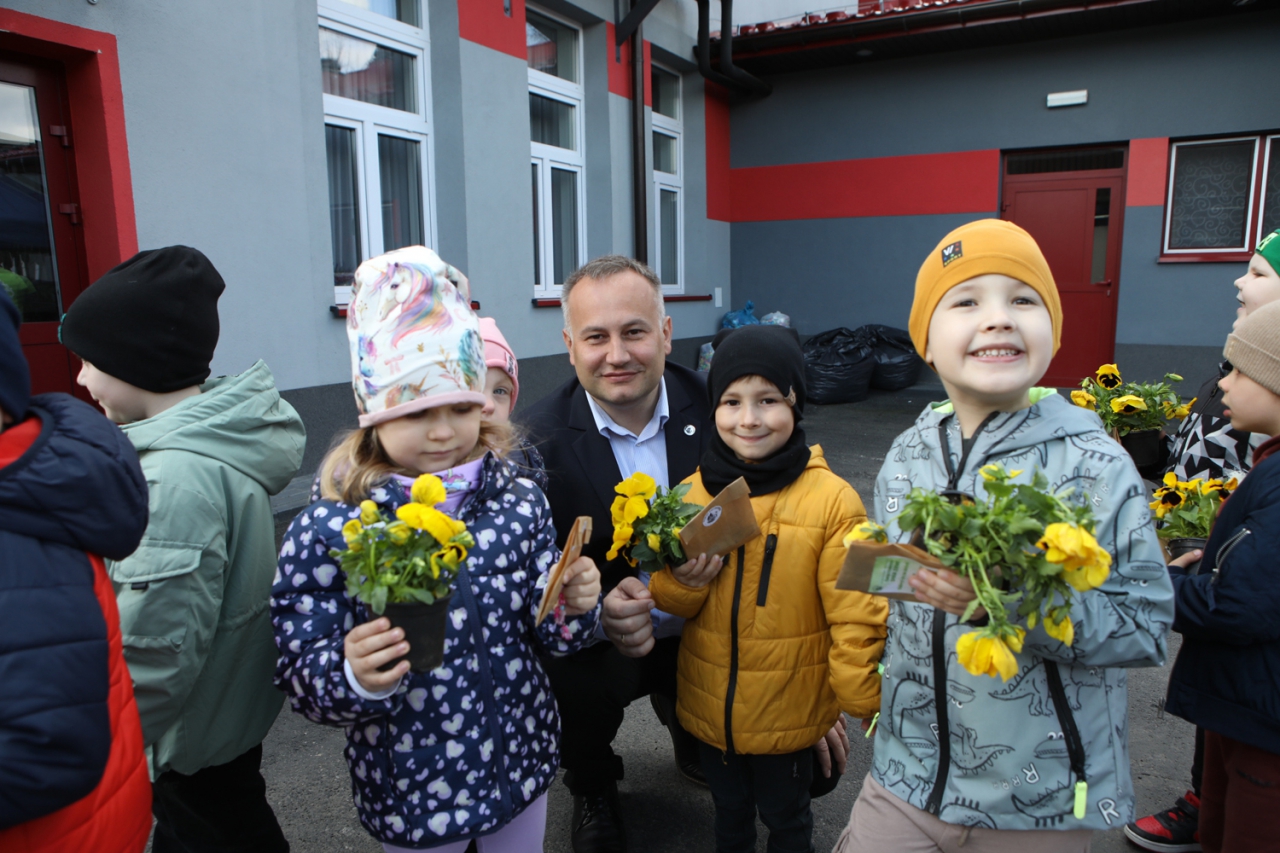 Dzieci z kwiatami wraz ze Starostą Wojtysiakiem który kuca