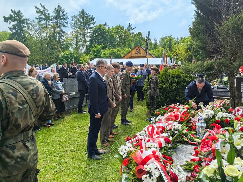 Wicestarosta Dariusz Magacz stoi przed grobem wraz z umundurowanymi uczniami