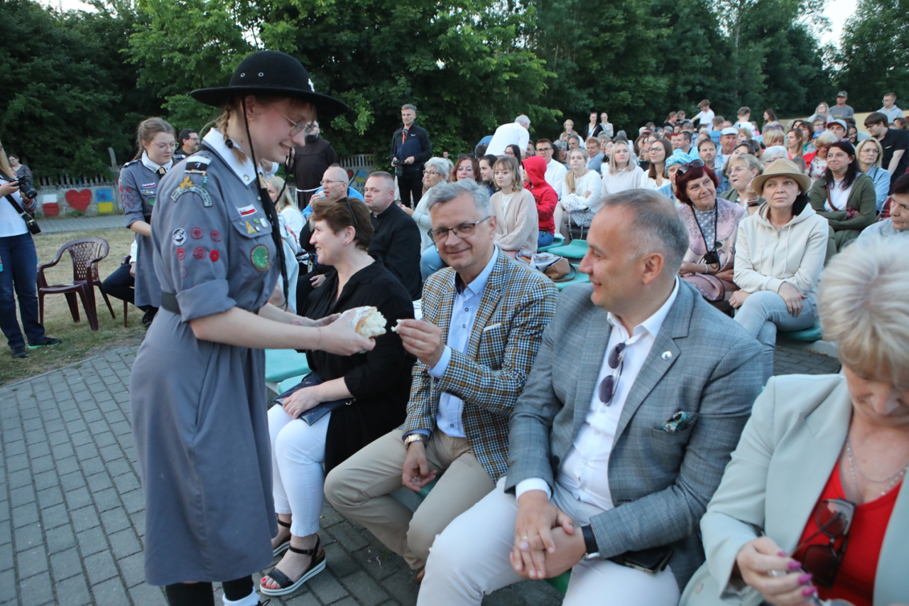 Starosta Piotr Wojtysiak oraz Wicestarosta Dariousz Magacz siedzą na widowni na świeżym powietrzu. W tle pozostali uczestnicy wydarzenia.